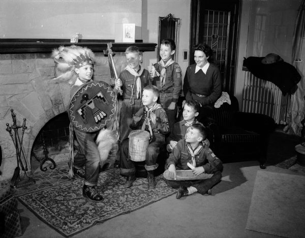 A group of Cub Scouts and their den mother Betty Smith look on as David Hill, in Native American costume (left), does a dance and Gary Lang beats a drum.