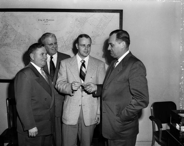 Portrait of four men, one of whom is probably Mayor George Forster, from the March of Dimes campaign. They seem to be giving the Mayor a ticket to the Charity Ball to be held on January 31.