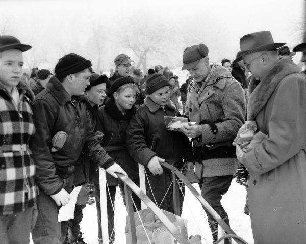 Dr. David Williams, center left, looks over first aid equipment prior to the Boy Scouts Klondike Derby at Glenway Golf Course. In the background are other men and a large group of scouts.