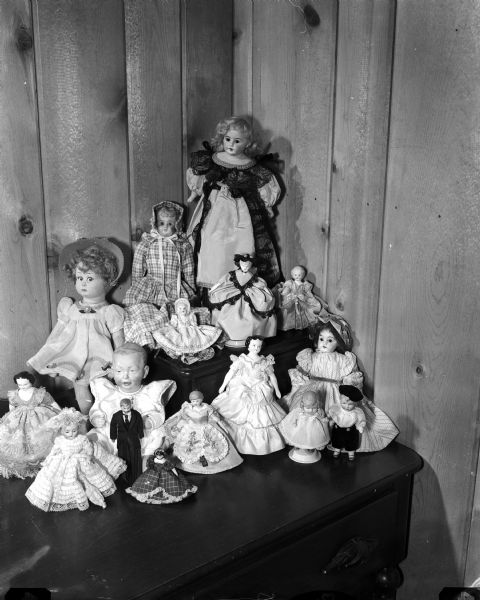 The doll collection of Mrs. Roman (Doris) Hilgers standing on a dresser, showcasing the fashion clothing she made for them.