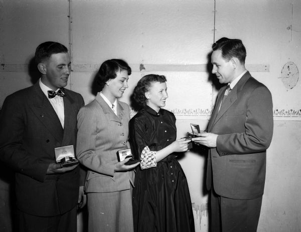 Three Dane County 4-H leaders are given gold wrist watches by William J. Kimball, Madison, County 4-H Agent, as awards for outstanding club work in state competition during 1951. Left to right: Russ Weisensel, Sun Prairie; Norma and Carol Fosshage, Mt. Horeb, and William Kimball.