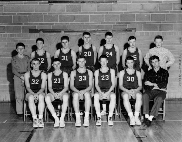 Group portrait of the New Glarus boys basketball team in uniform, with coach, James W. Stevens, and manager, Werner Bodenman.