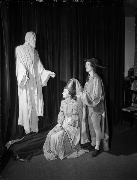 Two costumed actresses pose in front of a statue of Christ. Phyllis Brinkley, left, and Helen O'Brien, right, are lead players in "The Piper," a play presented by the Madison Woman's Club.