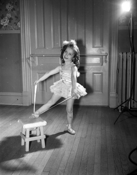 Mary Ellen Richards, age 5, poses while tying her ballet slippers. She is a pupil at the Kehl School of Dance.