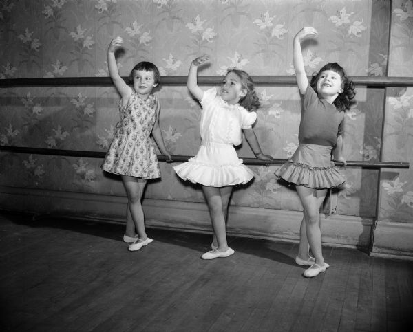 Three ballet dancers, pupils of the Kathryn Hubbard Dance Studio, practice ballet positions at the bar. They are, from left: Susan Barth, Rebecca Drescher, and Laurie Ann Baumeister.