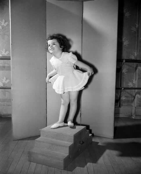 Portrait of Marsha Swenson, age 4, as she curtsies in a ballet costume. She is a student at the Katheryn Hubbard Dance Studio.