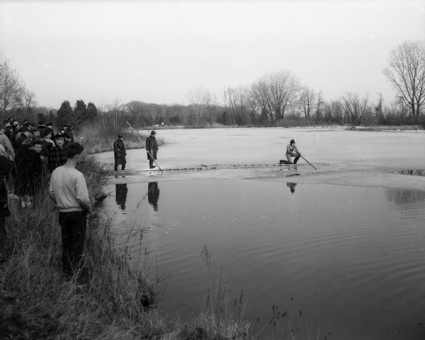 Carol Jean Brown, the six-year-old daughter of Donald and Eugenia Brown, 2917 Monroe Street, fell through the ice on the Lake Wingra lagoon near Arbor Drive. She was able to make her way to the shore and ran home. Firemen are shown as they spread ladders across the thin ice on Lake Wingra to search in the water to make sure that no children were still submerged.
