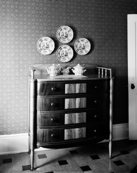 View of an antique chest of drawers in the home of Mr. and Mrs. Arthur J. Gafke in rural Fort Atkinson, Wisconsin. Hanging over the chest are four antique dishes.