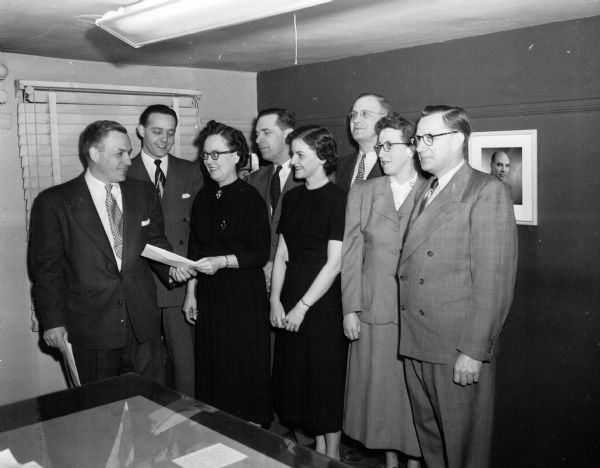Store manager Robert H. Anderson (left) hands out statements for the 1951 profits to six of the Sears, Roebuck, and Company employees who are members of the company's savings and profit sharing pension fund. To his left in the front row are: Mrs. Ruth Stoebler, Mrs. Mary Voth, Mrs. Irene Marquardt, and Stanley Hagen. In the back row, left to right, are: assistant manager Myron Sands, A.C. Breitenbach, and Edward Paska.