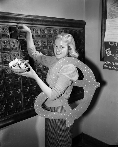 Nancy Wetzel, a finalist in the University of Wisconsin Prom Queen contest, is shown putting pretzels in the mail boxes at Elizabeth Waters Hall, as part of her "Take a Pretzel and Vote for Wetzel" campaign.