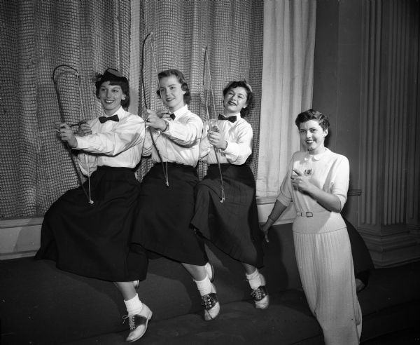 At extreme right is Lois Hunter, a finalist in the University of Wisconsin Prom Queen contest, with three Chi Omega sisters dressed in hunter's caps and carrying home-made bows and arrows as part of Hunter's "Aim for the Hunter" drive for votes. The "hunters" are left to right, Beverly Sager, Kari Reymert, and Jo Engel.
