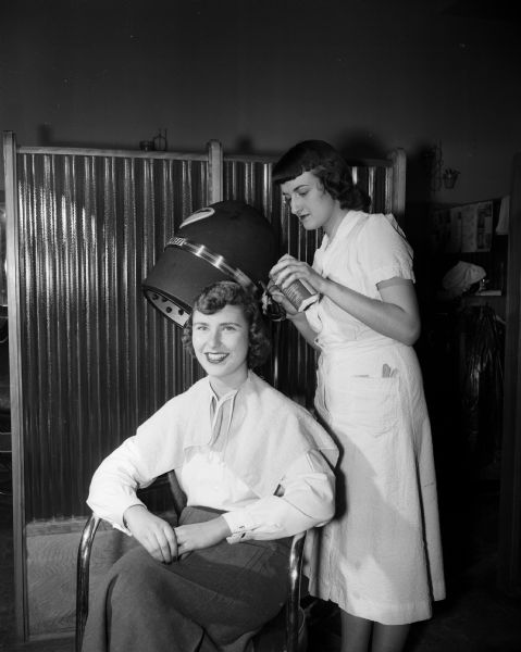 Sally Riblett, a finalist in the University of Wisconsin Prom Queen contest, is shown in a beauty salon getting her hair sprayed blue as part of her "The Girl With the Blue Hair" campaign for votes. The salon operator is Meredith Hansen.