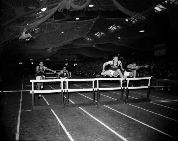 Don Voss, pictured second from the right, wins the 40-yard high hurdles during the Wisconsin-Northwestern Track Meet. Pictured from left to right are: Loid Atkinson of Wisconsin, Ray Cunningham of Northwestern, Don Voss, and Ed Duewell of Wisconsin.