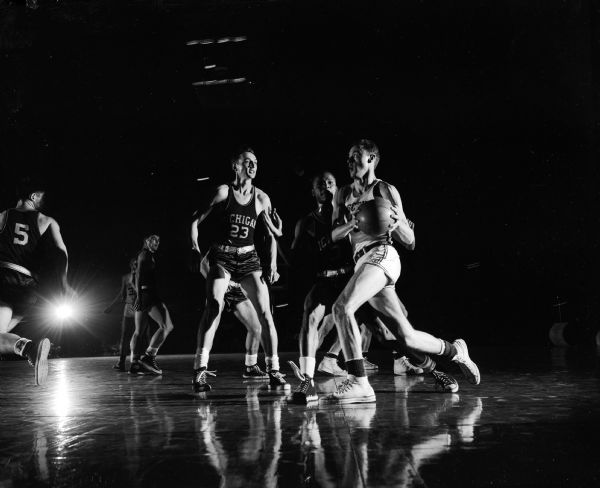 Albert "Ab" Nichols of Wisconsin drives for the basket during the basketball game between the Universities of Wisconsin and Michigan in the University of Wisconsin-Madison Field House. Guarding Nichols are Milton Mead (23) and Donald Eddy (2) of Michigan. Wisconsin won the game 69-53.