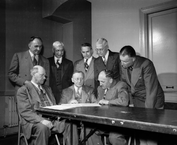Officers of the one-hundred-year-old Maennerchor male choir gather around a table. Seated (left to right) are: Henry Loeprich, banquet chairman; Otto A.W. Niemann, president; and Herman Postweiler, vice-president. Standing (left to right) are: Rudy Postweiler, secretary; Felix Odenahl, advertising chairman; August Haak, social chairman; George Schaus, librarian; and Paul Bernard, treasurer. The group is Wisconsin's oldest singing society.
