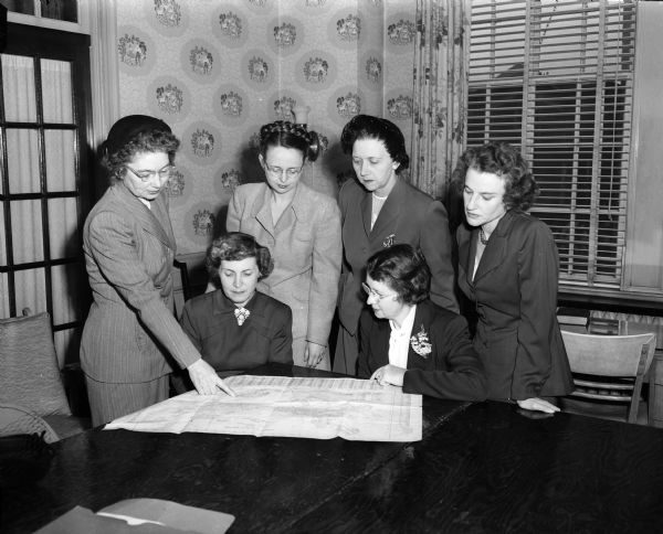 Group portrait of some of the Madison women who are assisting with plans for the YWCA membership round-up. Seated are: Mrs. Harold F. (Marion) Brandenburg, left, and Mrs. Fred M. (Altha) Smith. Standing, left to right, are: Mrs. Ralph (Dorothy) Benedict, Mrs. C.H. (Jeanette) Ruedisili, Mrs. Floyd (Muriel) Chapman, Mrs. Ernest R. (Bettylou) Anderson.