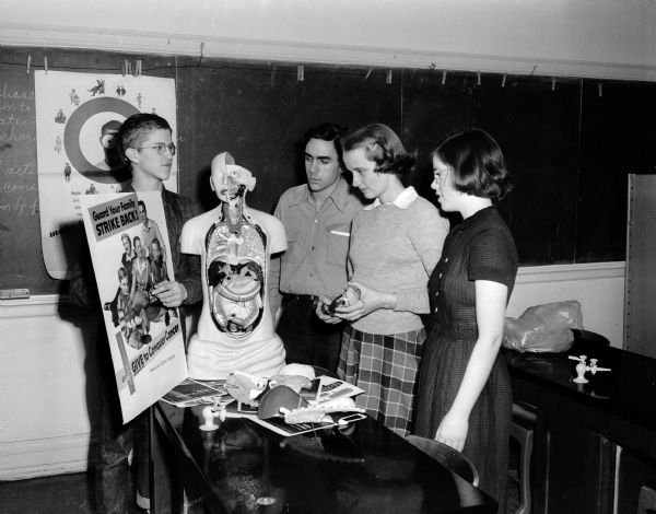 Making plans for Cancer Education Week, members of the Wisconsin High School science club are shown with "Careless Charlie,' inspecting posters. From left to right are: Paul Treichel, Don Russell, Margot Herman, president, and Cornelia Mack, secretary-treasurer.