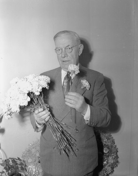 J. Edward O'Connell, an assistant cashier at First National Bank, with some green carnations. He traditionally hands out green carnations to one hundred fifty bank employees on St. Patrick's Day.