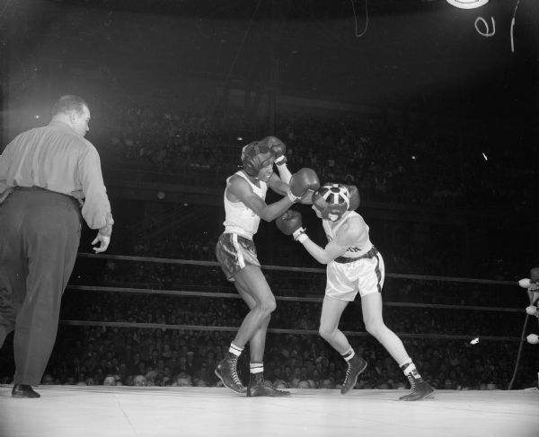 Herb Odom, Michigan State boxer on left, is blocking Bobby Morgan's right to the head. Bobby Morgan, on right, is a University of Wisconsin boxer. The match was held in the University of Wisconsin-Madison Field House.