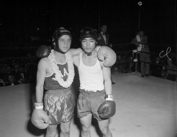 Roy Kuboyama, Hawaii, is shown with Jules Stoltz, Miami, after he draped a lei of carnations flown from Hawaii on Stoltz. Kukboyama decisioned Stoltz in the 112-pound bout that opened the NCAA semi-finals at the University of Wisconsin-Madison Field House.