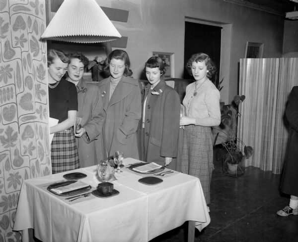 Five girls from Edgewood High School, in Madison, are looking at a display of table settings.  Loeft to right are Catherine Burmeister, Mary Boltz, Yvonne Reagan, Judy Hagen and Mary Huth.