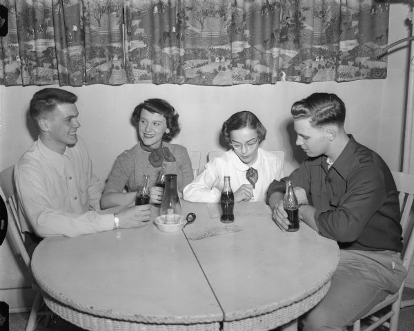 Representatives of four Madison high schools completing plans for the skirt and sweater dance to be given for senior high school students under the sponsorship of the Y-Teen Co-ed Council.  Among those on the dance committee are, from left to right: Tom Stephan, West High School; Lorraine Emordeno, Central; Charlotte Burns, Wisconsin high; and Terry Howe, East.