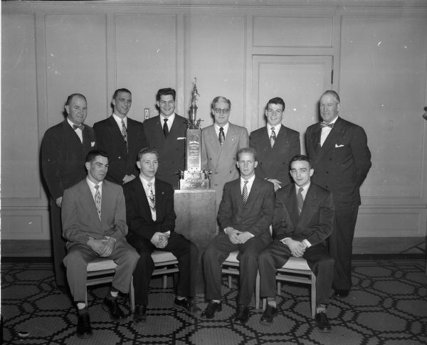 University of Wisconsin-Madison coaches and the eight Badger boxers who were entered in the 15th annual National Collegiate Athletic Association (NCAA) boxing tournament in which Wisconsin won the team championship. The large trophy between Co-Captains Bobby Ranck and John R. (Dick) Murphy (both standing) is the John J. Walsh Trophy which is emblematic of the NCAA team championship.