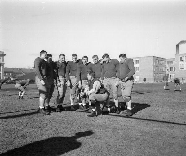 Milt Bruhn, line coach for the University of Wisconsin-Madison football team, greeting eight of the team's tackles at the opening of spring practice. These eight tackles range in weight from about 200 pounds to 270 pounds.