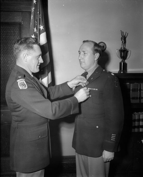 Major William E. Neidner, (left) a member of the staff of the senior Army instructor of the Wisconsin National Guard, presenting the Bronze Star Medal to Lt. Col. Carlisle P. Runge (right), a general staff officer of Wisconsin's 32nd National Guard division. The medal was awarded for meritorious service in Europe during World War II while commander of the 242nd Quartermaster Depot Company in operations against the enemy from 1943 to 1945.