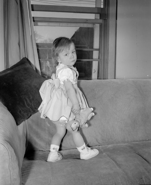 Portrait of twenty-month-old Emily Jane Kiekfofer standing on a sofa.