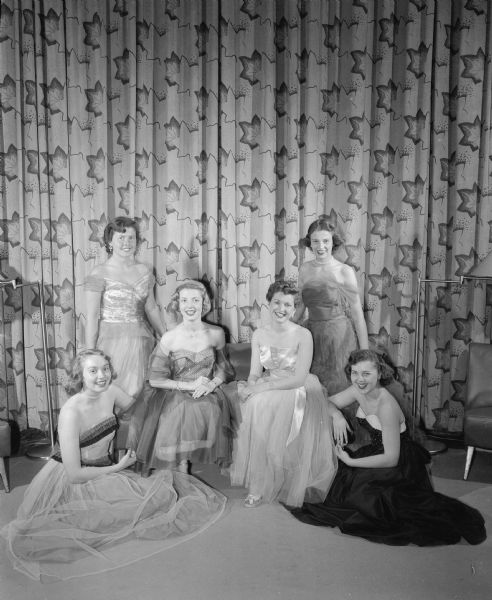 Six university co-eds who served as the court of honor at the University of Wisconsin-Madison's 36th Military Ball. Seated on the floor are Barbara Hall, left, and Lois Small, right.  Seated on the love seat are Jeanne Froehlig, left, and Patricia Franklin, right.  Standing are Phyllis Indermeuhle, left, and Margaret Terrill, right.