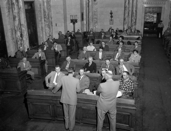 Elevated view of some of the nearly 70 farmers and their wives from nine Wisconsin counties gathered in the state assembly chamber to hear a discussion of farm deferments by the State Selective Service Director Bentley Courtenay, and the group leader Adolph Maasen.
