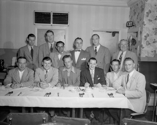 Group portrait of twelve men in front of a dinner table, possibly at a bowling alley.