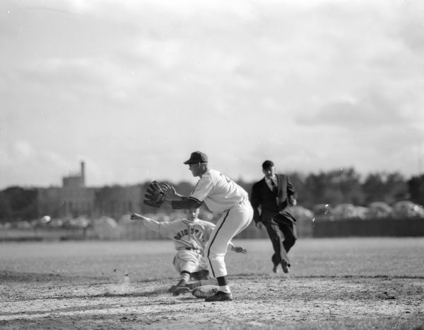 University of Wisconsin vs. Ohio State Baseball game at Lowman Field.  Badger third baseman Jack Baumgarten awaits the throw from the short-stop player as Ohio State player Jack Ganson slides safely into third base. The umpire is Art Lutz.