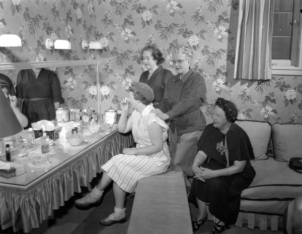 Four women golfers in the ladies' lounge of the Nakoma Country Club.  Seated is Lucille Nedrebo, president of the Nakoma Women's group.  Standing, left to right: Elizabeth Parker, social chairman, Mrs. William McCormick; and Myrtle Jamieson, hostess for the day.