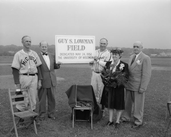 Ceremony dedicating the new baseball diamond to Guy S. Lowman, who was the head coach in three sports at the University of Wisconsin at one time, and was the head baseball coach for many years. Pictured, left to right, are: Michigan coach Ray Fisher, Wisconsin Athletic Director Guy Sundt, Wisconsin coach Arthur Mansfield, Mrs. Lowman, and University of Wisconsin president Edwin B. Fred.