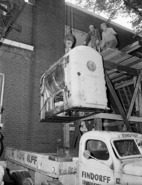A Findorff truck is moving one of three eight-and-a-half bread mixers from the old plant of the Gardner Baking Company at 849 East Washington Avenue to the new bakery building at 3401 East Washington Avenue. The move was made without losing a single loaf of bread.