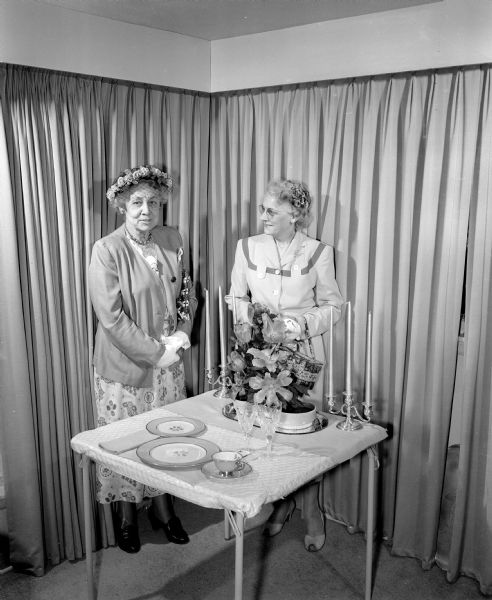 Garden show and tea at which the West Side Garden Club entertained other garden clubs of the Madison area. Mrs. George Harbort, left, and Frances T. (Mrs. J.J.) Prokop, right, admiring a formal dinner table setting with a cut flower arrangement of parrot and Darwin tulips.