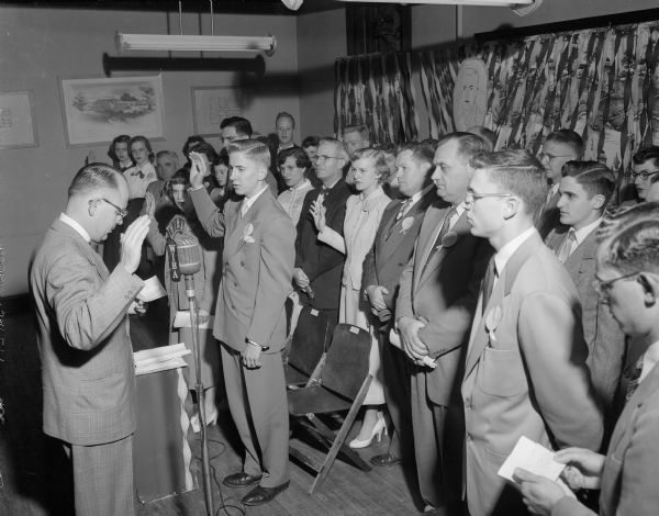 Alderman Donald Viereg, second ward, at left, swears in Dick Hilden, the new East side youth mayor (directly in front of Viereg), and thirty youth members of the cabinet and council in the East Side Businessmen's Association club room.