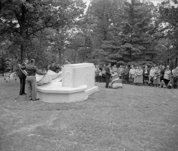 The unveiling of a marble monument dedicated to Madison's war dead at Forest Hill Cemetery as part of Madison's Memorial Day ceremonies. At the right of the monument is Attorney Lyall T. Beggs, past national commander of the Veterans of Foreign Wars, who delivered the address.