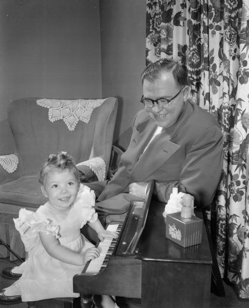 Wilbur J. Schmidt, 1221 E. Johnson Street, watches his two year old daughter, Linda play with her toy piano. The photograph was part of a newspaper feature on fathers and their children.