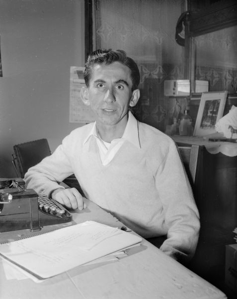 George Tymorek, seated at a typewriter, is the son of Polish immigrants. He grew up in Chicago Heights, Illinois, and received his Master of Arts degree in Comparative Literature at the University of Wisconsin.
