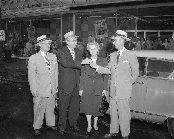 Robert J. Widmer accepts the keys for a new Nash Rambler that he won for his entry in the window display contest for Lee hats. His display was named the best of hundreds from all parts of the country. In the picture are, left to right: W.M. Harris, president of Olson and Veerhusen whose store they are in front of at 7 North Pinckney Street; Larry Anderson, New York, a representative of Lee Hats; Mildred Widmer; and Robert.