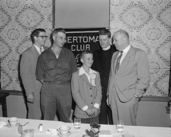 Bobby Dommershausen, entrant in the 1952 Soap Box Derby, is pictured with members of the Sertoma club which sponsored him. Sertoma members shown left to right are Roland (Bud) Paul, Ralph Vogel, Rev. Jerome Mersberger, and Frank Bottomer.
