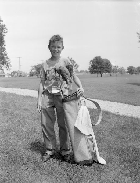 Steven George Eisele posing outdoors with his golf clubs.