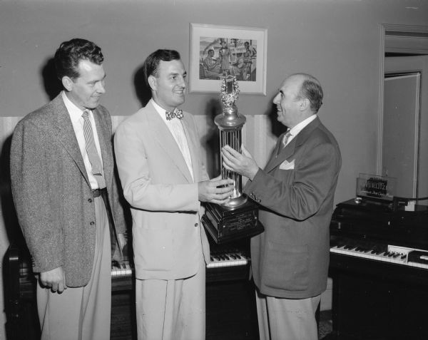 Forbes-Meagher Music Co., 27 W. Main Street, won a trophy in a nation-wide window display contest. A.C. Cory (right) presenting the trophy to Harold Frye (center) as H.M. Goepforth (left) is looking on.