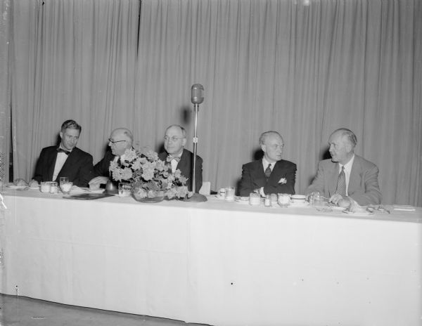 The head table at the University of Wisconsin Alumni Association banquet at the Memorial Union. Left to right are: State Senator Warren P. Knowles, president-elect; University President E.B. Fred; Willard Aschenbrener, retiring president; John W. McPherrin, publisher of the American magazine, principal speaker; and John Berge, executive secretary. 
