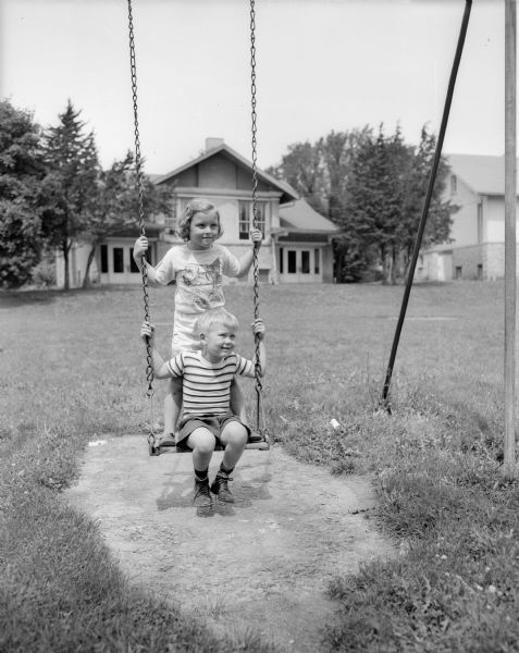 Jean Christenson and Craig Olafsson playing on a swing at the Shorewood Hills Play School, a summer recreation program at Shorewood Hills schools and parks.