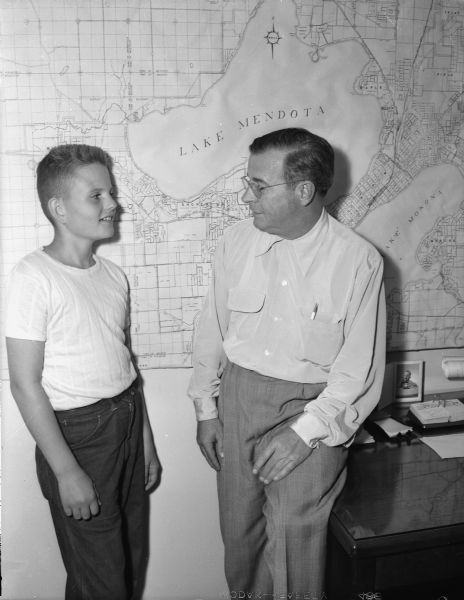 Soap box derby racer Johnny Rothman (left) talks over "victory plans" with his sponsor Roy A. Gannon, of Gannon Real Estate Company, at the realtor's office.