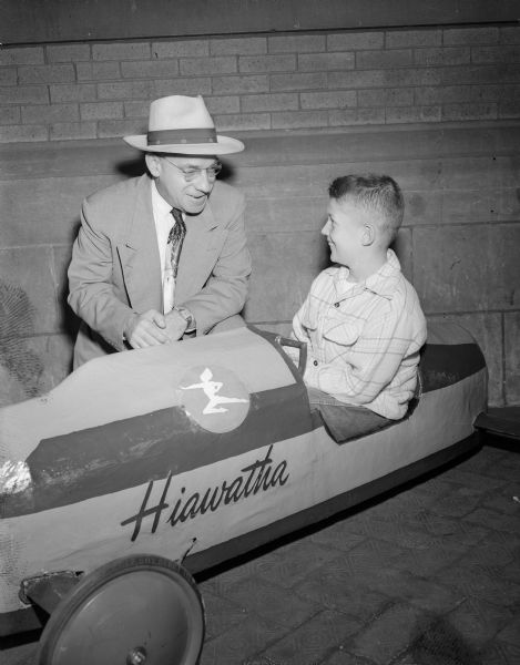 A.J. Farnham, superintendent of the Chicago Milwaukee St. Paul & Pacific Railroad's Madison division, admires Phil Peckham's soap box derby racer which was designed to resemble the Milwaukee Road's Hiawatha.